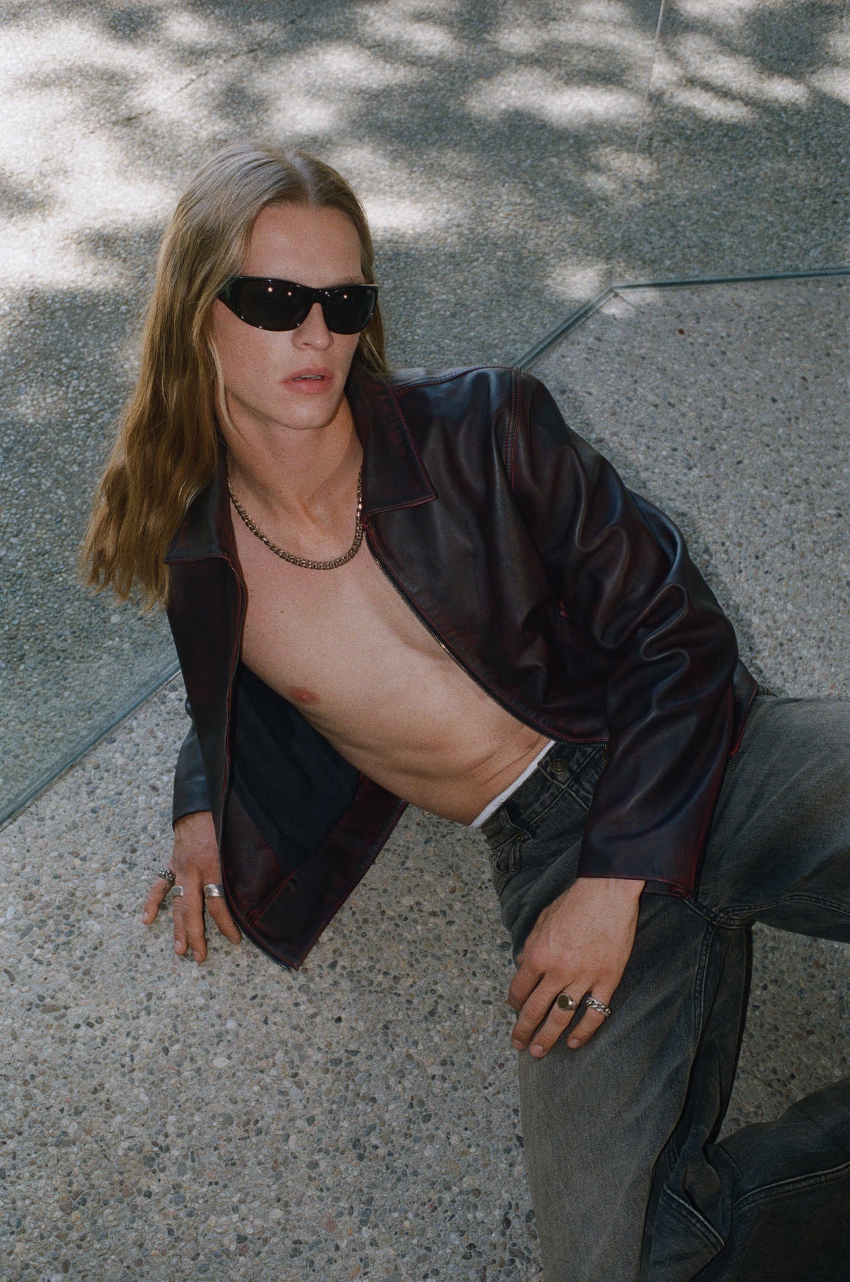 Overhead portrait of a model in sunglasses and an open dark jacket.
