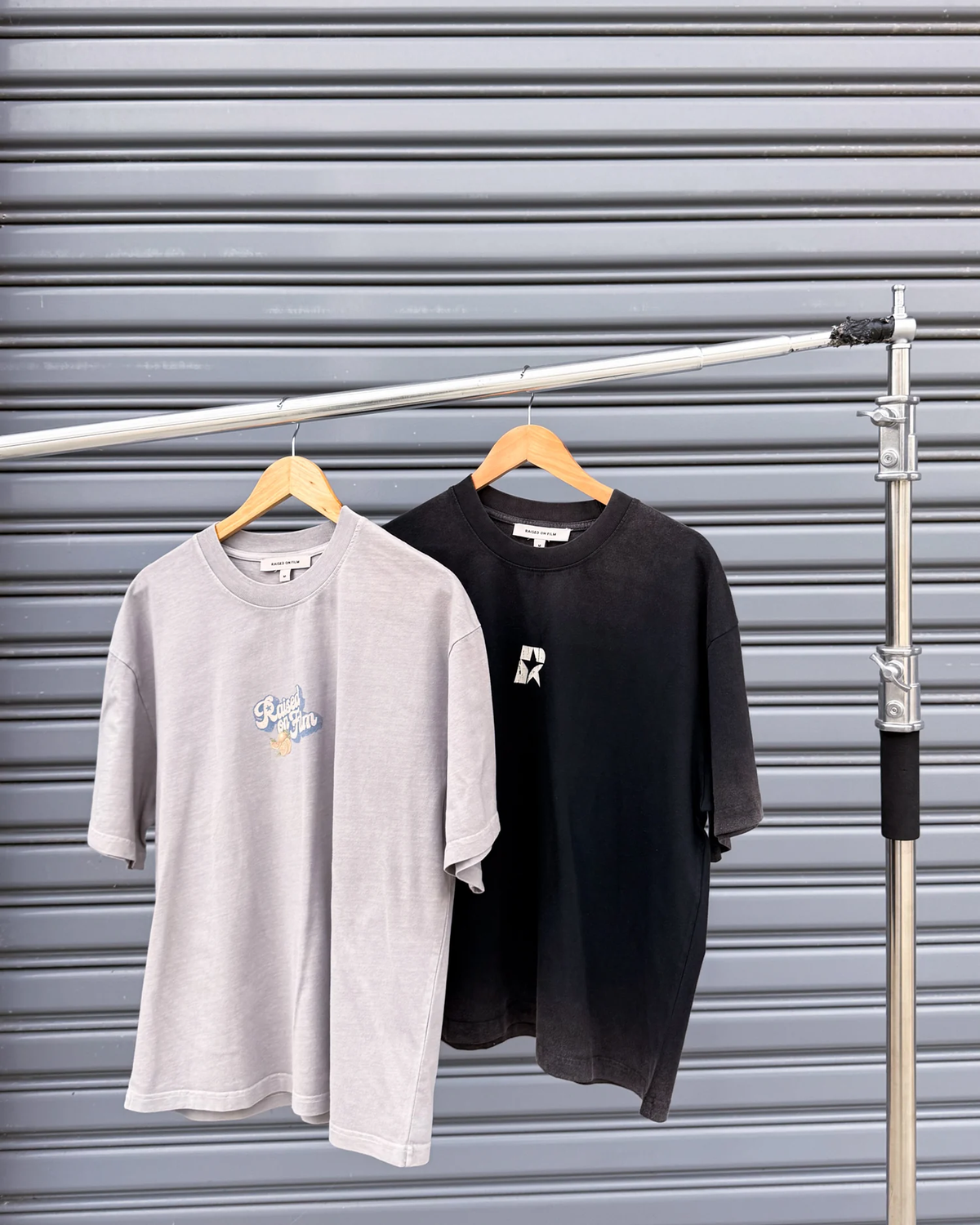 Grey and black cotton graphic T-shirts hanging from a studio rail.
