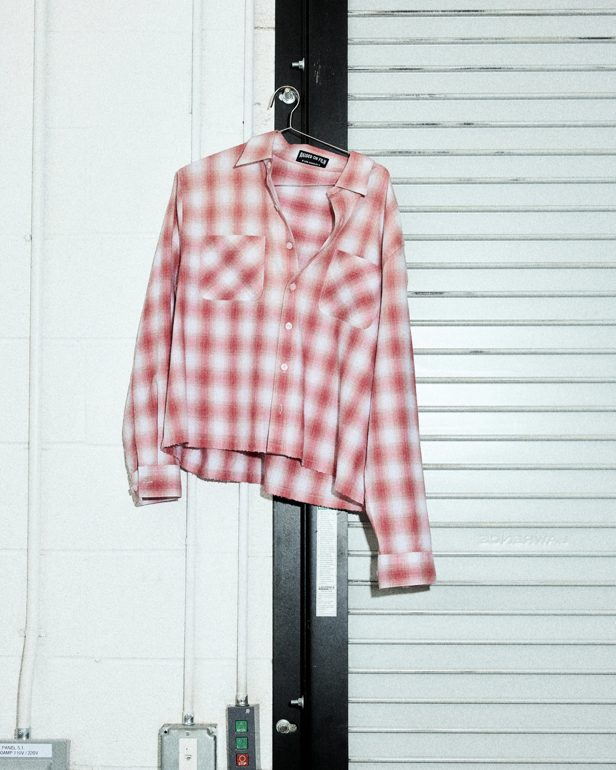 Red L.A. Flannel shirt hanging against a pale studio shutter.
