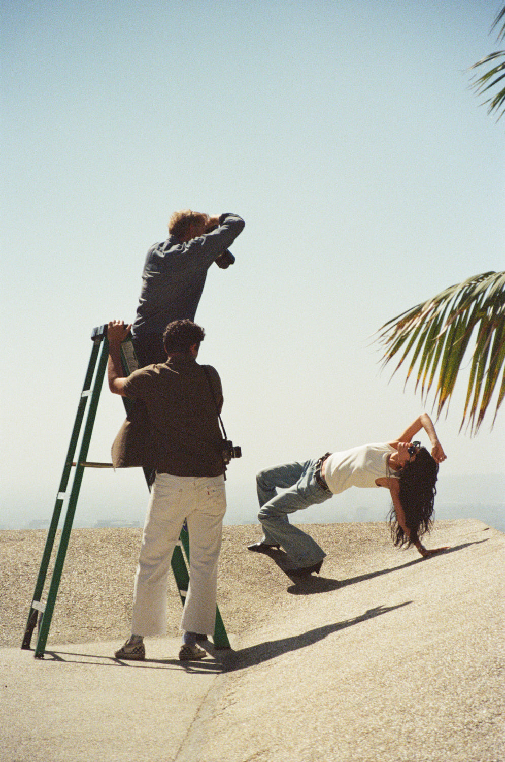 Film cameras, lenses, light meters and Polaroid photographs arranged on grey fabric.