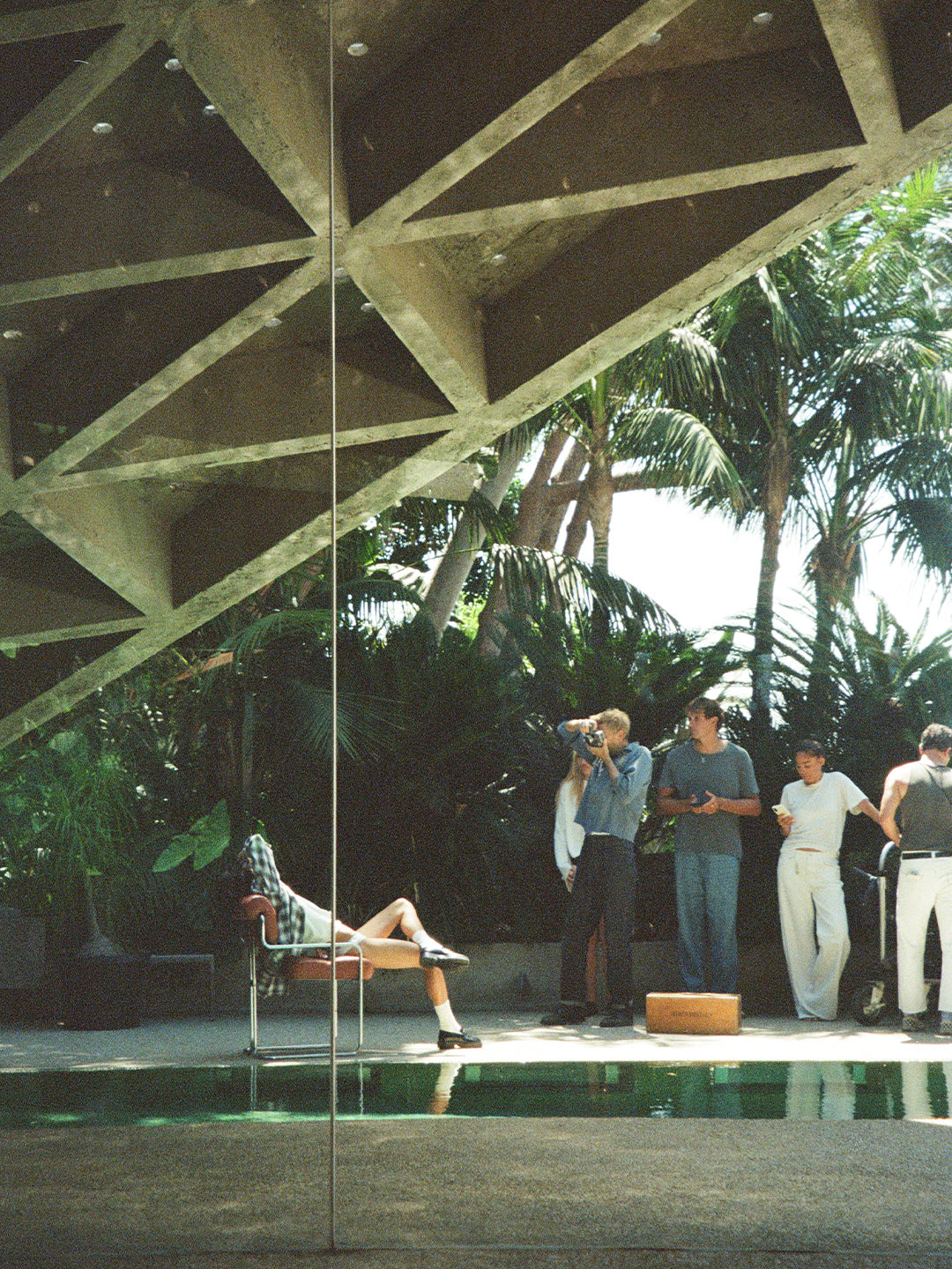 A photographer and crew beside a pool beneath a timber roof.