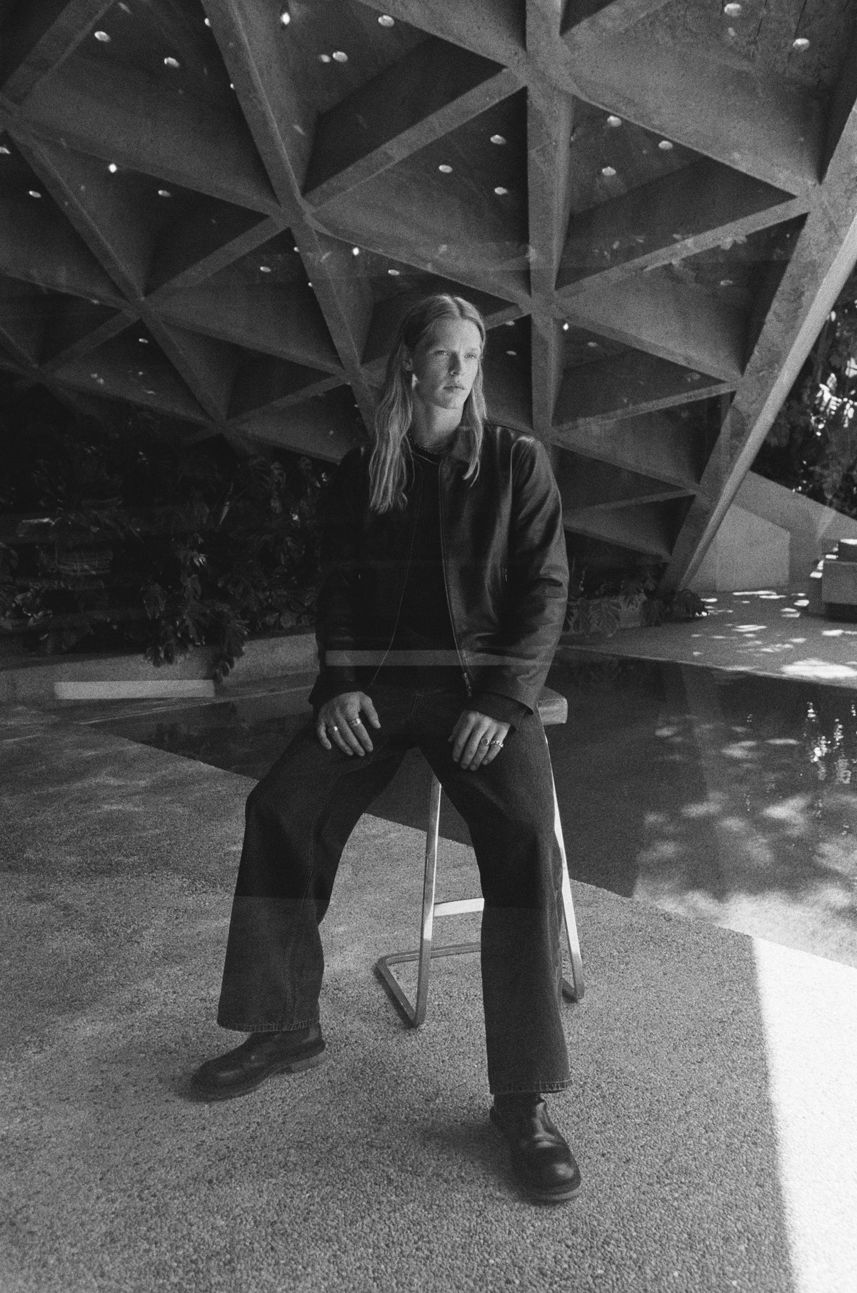 Black-and-white photograph of a seated model beneath the geometric roof.