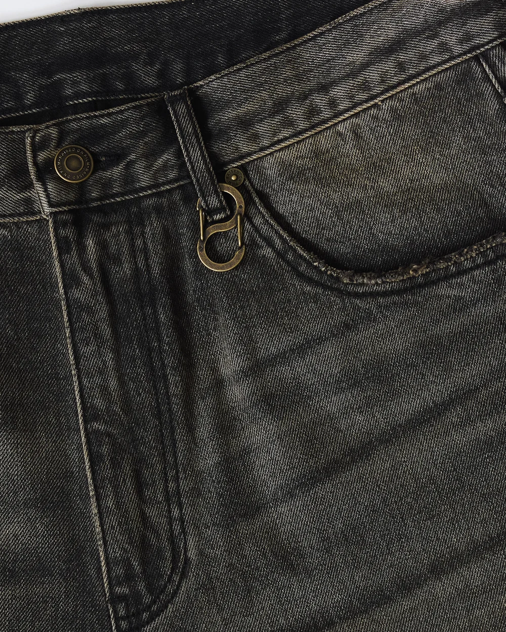 Close-up of washed denim, waistband stitching and front pocket.