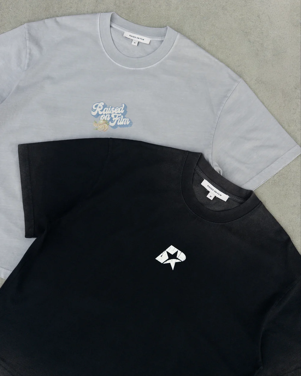 Close-up of grey and black cotton T-shirts showing their printed graphics.
