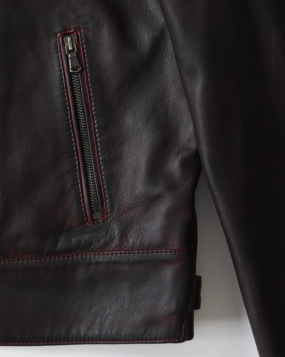 Close-up of the Hudson Jacket showing red lamb leather, pocket zip and stitched hem.